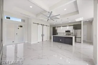 Kitchen with a barn door, light tile flooring, beamed ceiling, and stainless steel appliances