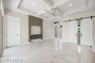 Unfurnished living room with beamed ceiling, a barn door, and light tile floors