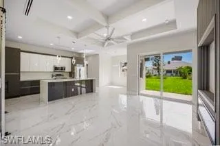 Kitchen featuring coffered ceiling, beamed ceiling, light tile flooring, and white cabinetry