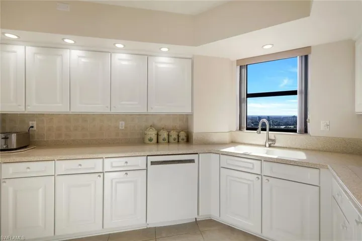 Kitchen with white cabinets, sink, and white dishwasher
