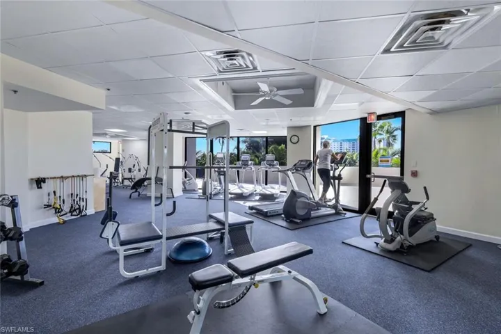 Exercise room featuring a paneled ceiling, ceiling fan, and expansive windows