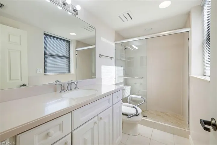 Bathroom with tile patterned floors, vanity, toilet, and a shower with shower door