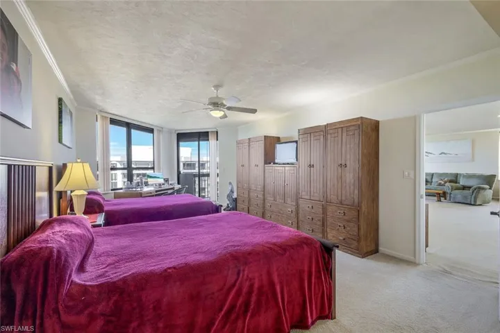 Carpeted bedroom with ceiling fan, ornamental molding, and a textured ceiling
