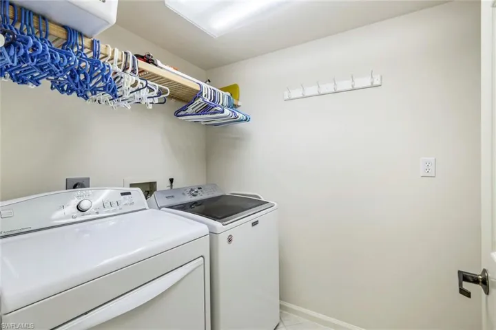Laundry room with light tile patterned flooring and washing machine and clothes dryer