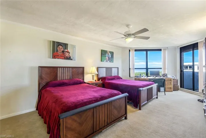 Carpeted bedroom featuring ceiling fan, crown molding, a wall of windows, and a textured ceiling