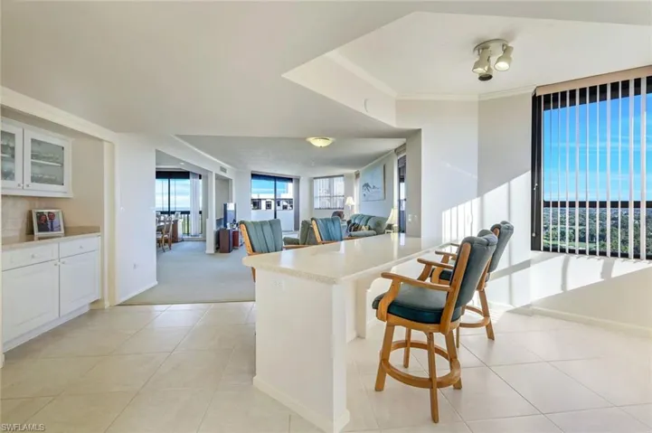 Kitchen with a breakfast bar, white cabinets, light tile patterned floors, and ornamental molding