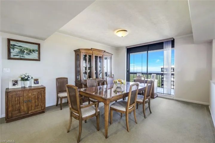 Dining area with crown molding and light carpet