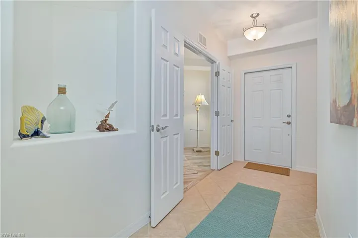 Foyer with light tile patterned flooring and baseboards