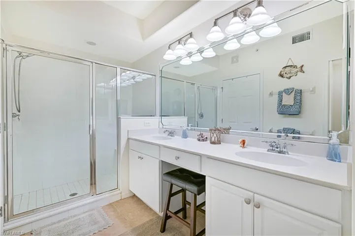 Full bath with double vanity, a stall shower, and light tile patterned flooring