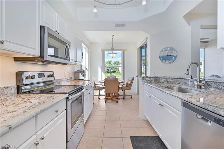 Kitchen featuring appliances with stainless steel finishes, light stone counters, white cabinets, and light tile patterned floors