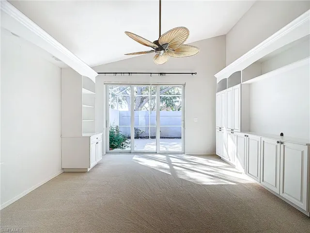 Carpeted empty room featuring lofted ceiling and ceiling fan