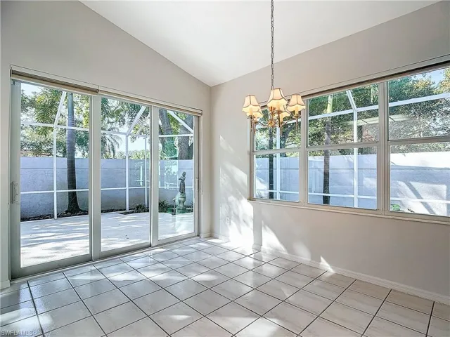 Unfurnished dining area with a wealth of natural light, lofted ceiling, and light tile floors