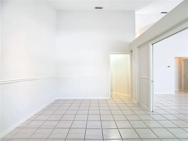 Tiled spare room featuring a towering ceiling