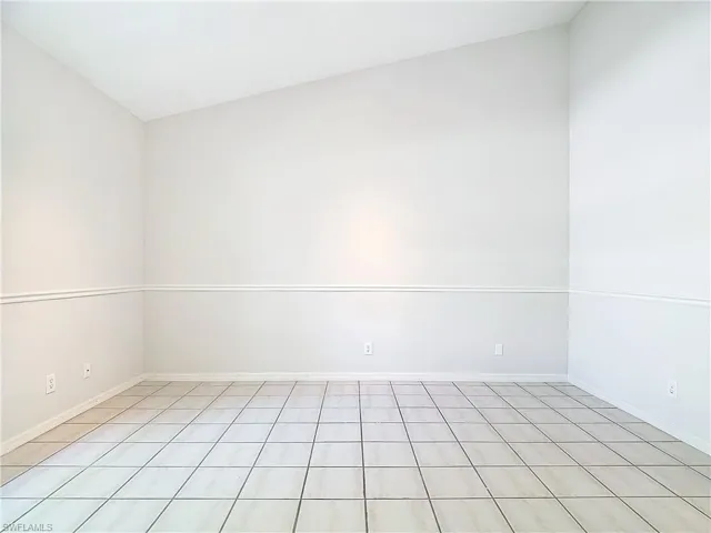 Tiled empty room featuring lofted ceiling