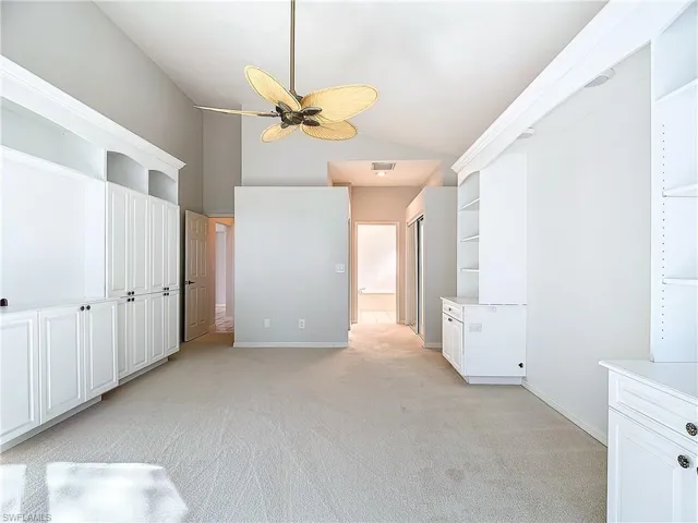 Carpeted empty room with ceiling fan and lofted ceiling