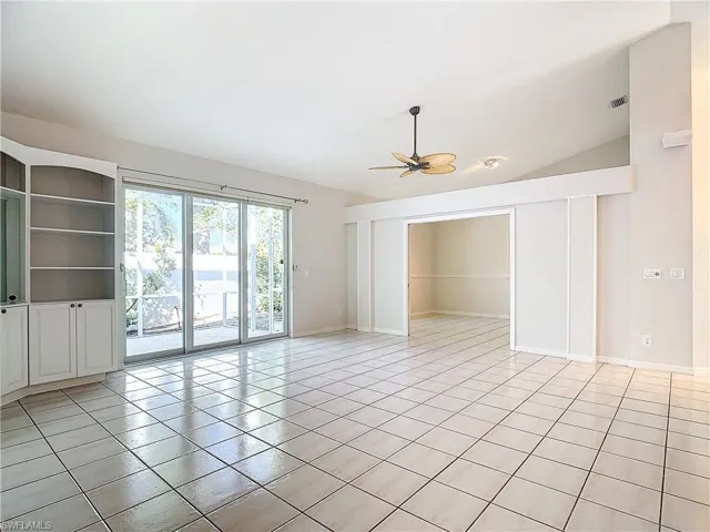Unfurnished room with ceiling fan, lofted ceiling, and light tile floors