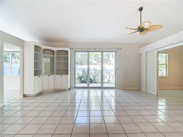 Tiled empty room with a wealth of natural light and ceiling fan