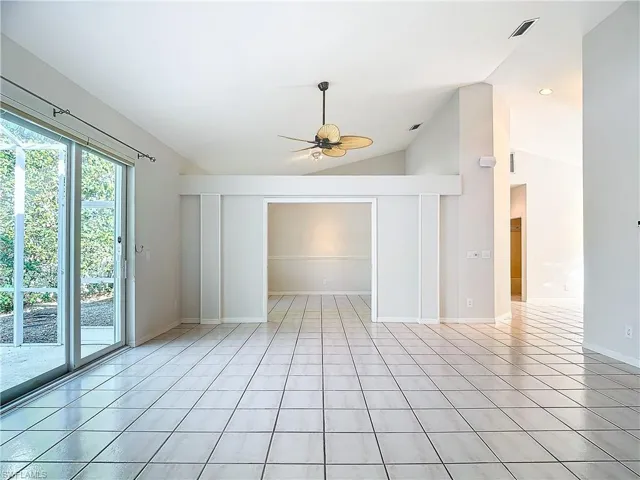 Tiled empty room with ceiling fan and lofted ceiling