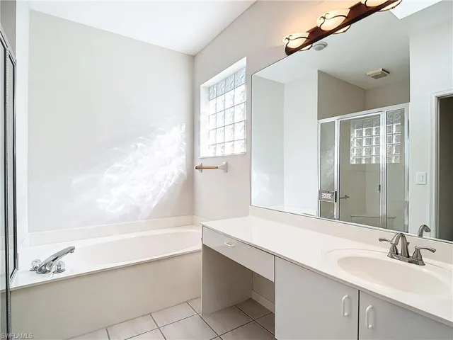 Bathroom featuring tile flooring, separate shower and tub, and vanity