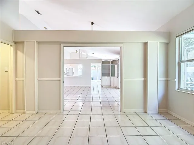 Tiled empty room featuring vaulted ceiling and a wealth of natural light