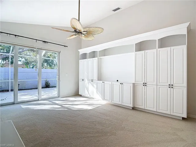 Carpeted spare room featuring high vaulted ceiling and ceiling fan