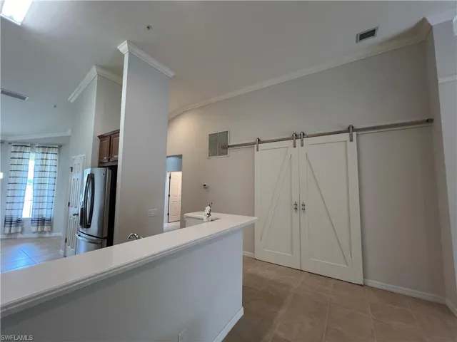Kitchen with ornamental molding, light tile patterned flooring and stainless steel fridge
