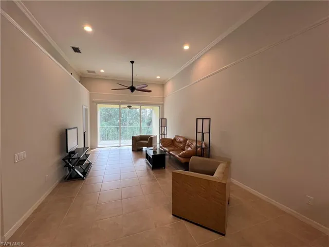 Living room with ornamental molding, light tile patterned flooring, and ceiling fan