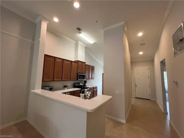 Kitchen featuring crown molding, appliances with stainless steel finishes, kitchen peninsula, and light tile patterned floors