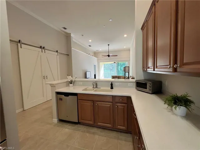 Kitchen featuring sink, dishwasher, a barn door, kitchen peninsula, and ceiling fan