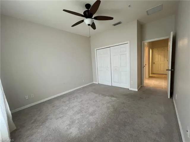 Unfurnished guest bedroom featuring a closet, ceiling fan, and brand new carpet