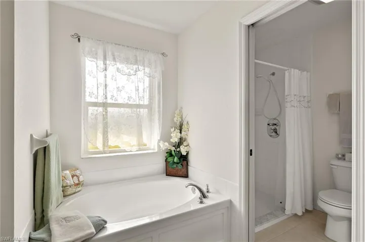 Bathroom featuring separate shower and tub, toilet, and tile patterned flooring