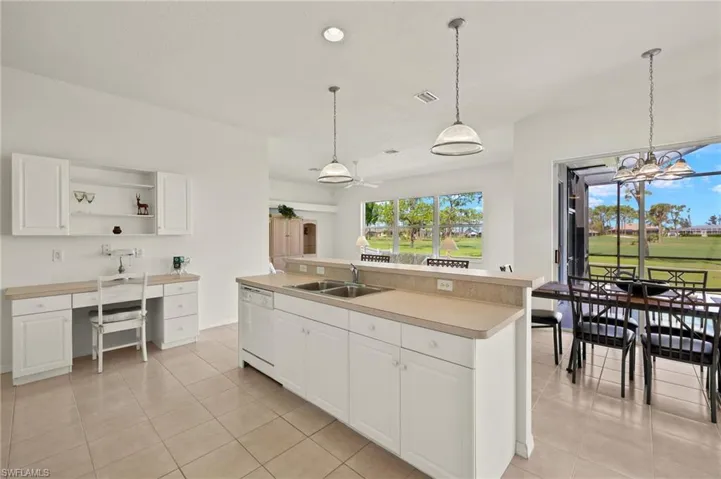 Kitchen featuring white dishwasher, sink, an island with sink, and white cabinets