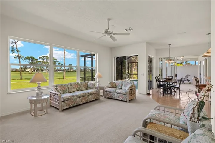 Living room with a textured ceiling, carpet floors, plenty of natural light, and ceiling fan with notable chandelier