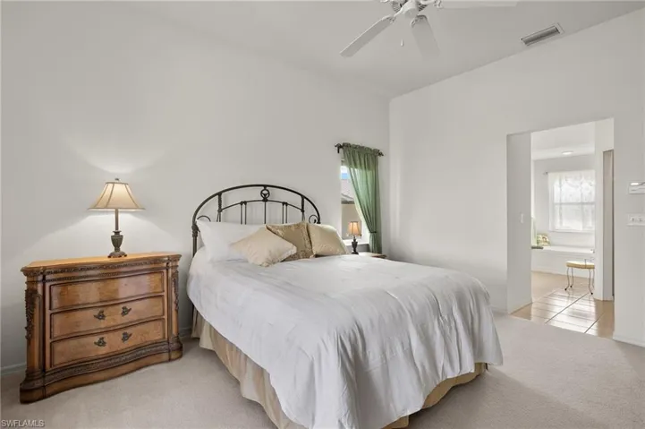 Bedroom featuring connected bathroom, ceiling fan, and light carpet