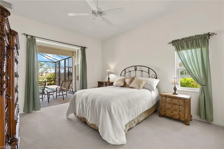 Carpeted bedroom with ceiling fan, multiple windows, and access to exterior