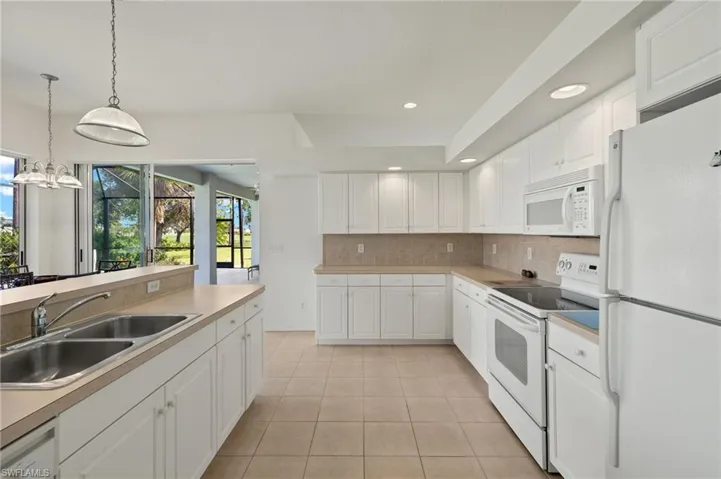 Kitchen featuring sink, a notable chandelier, light tile patterned floors, white cabinets, and white appliances