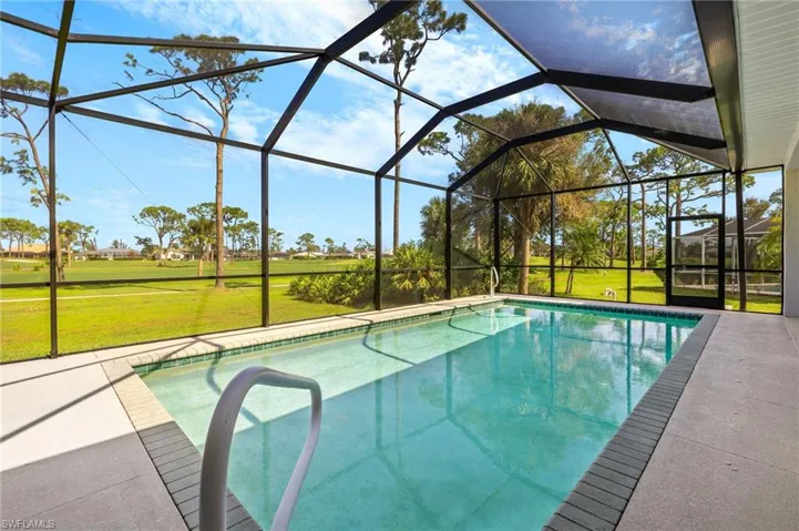 View of swimming pool featuring a yard, a patio, and glass enclosure