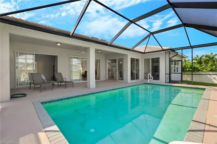 View of pool featuring a patio area, ceiling fan, and glass enclosure