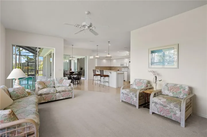 Carpeted living room with ceiling fan with notable chandelier