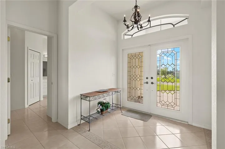 Tiled foyer featuring french doors and a notable chandelier