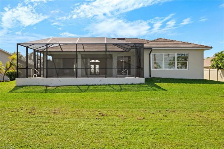 Rear view of property with a lawn and glass enclosure