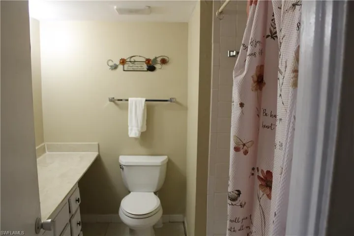 Bathroom featuring walk in shower, tile patterned floors, vanity, and toilet