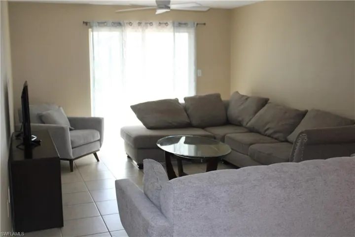 Living room with ceiling fan and light tile patterned floors