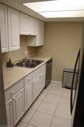 Kitchen with dishwasher, white cabinetry, sink, and light tile patterned floors