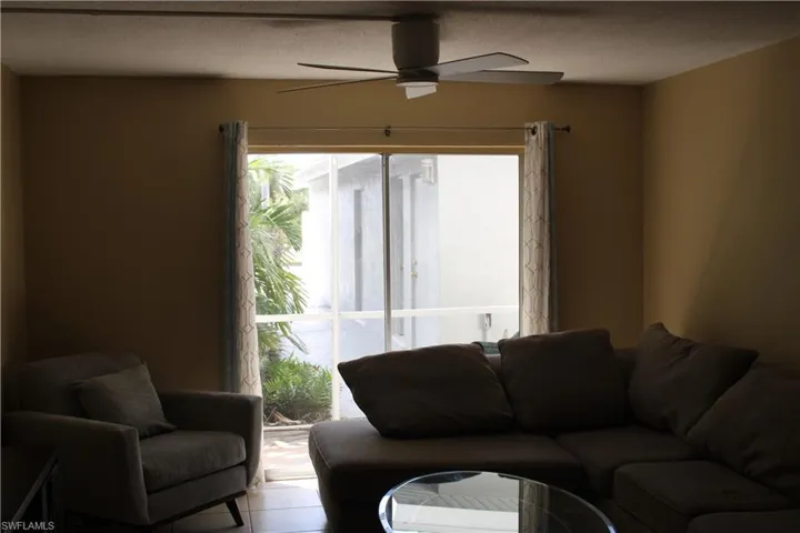 Living room featuring a textured ceiling, ceiling fan, and light tile patterned flooring