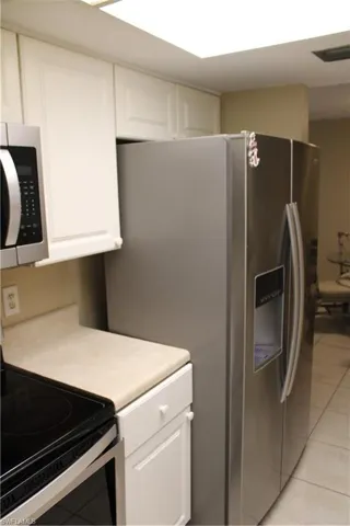 Kitchen featuring white cabinetry, appliances with stainless steel finishes, and light tile patterned floors