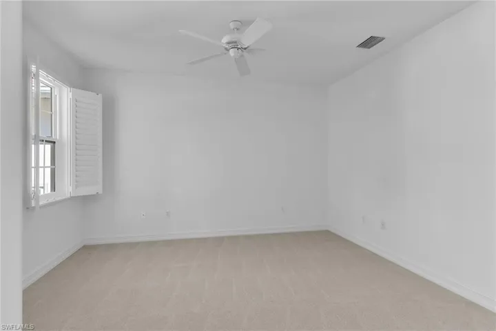 Den with light carpet and a ceiling fan.
