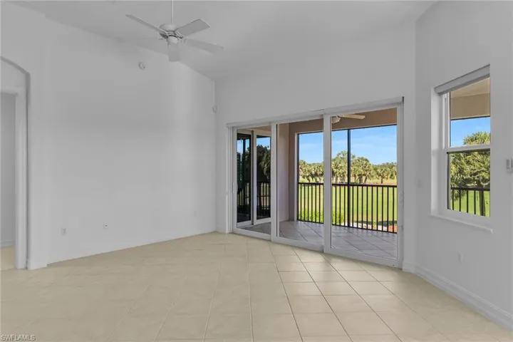 Living room with ceiling fan and light tile patterned flooring.