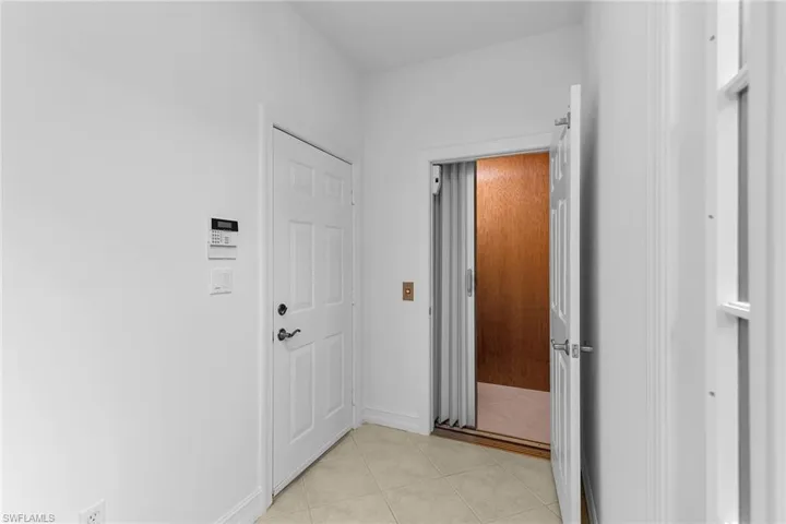 Hallway with light tile patterned floors and elevator.