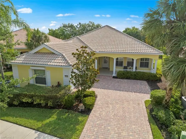 Mediterranean / spanish house with a tiled roof, covered porch, stucco siding, and decorative driveway